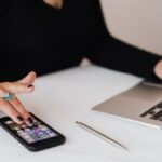 Mobile SEO - Crop woman using smartphone and laptop during work in office