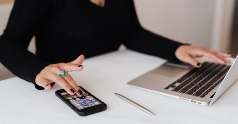 Mobile SEO - Crop woman using smartphone and laptop during work in office