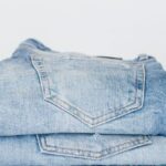 Market Trends - Pile of denim pants of different shades of blue placed on white shelf