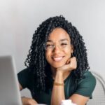 Content Repurposing - Happy ethnic woman sitting at table with laptop