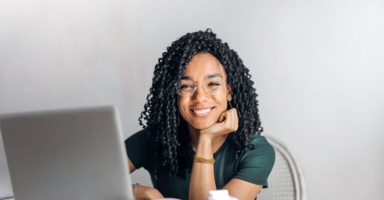 Content Repurposing - Happy ethnic woman sitting at table with laptop