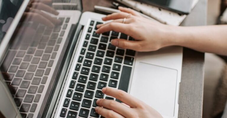 Technical SEO - From above of unrecognizable woman sitting at table and typing on keyboard of computer during remote work in modern workspace