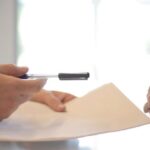 Marketing ROI - Crop businessman giving contract to woman to sign