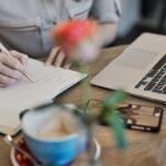 Content Marketing - Person Writing On A Notebook Beside Macbook