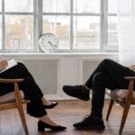 E-Commerce Analytics - Person in Black Pants and Black Shoes Sitting on Brown Wooden Chair